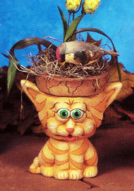 A small cast ceramic figure of a cartoonishly styled seated cat. Its head is hollowed out and topped with a rim like a garden pot. Its triangular ears poke out to the sides of the rim as it stares forward with round eyes.