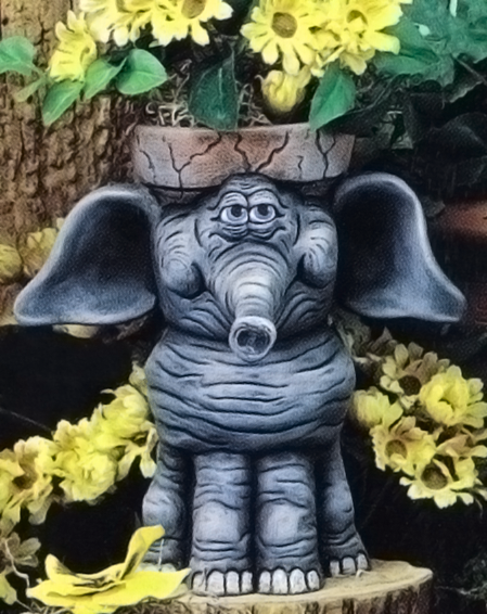 A cast ceramic figure of a cartoonishly styled standing elephant. Its head is hollowed out and topped with a rim like a garden pot. Its large ears protrude from either side of the pot and its trunk points forward. Its feet are wide.