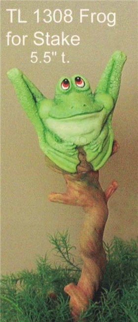A cast ceramic figure of a cartoonish frog. It sits with bent legs and looks up with a calm smile. It is placed as if perching atop a stake also made of cast ceramic and shaped to look like a weathered branch. The stake is placed into the soil of a pot.