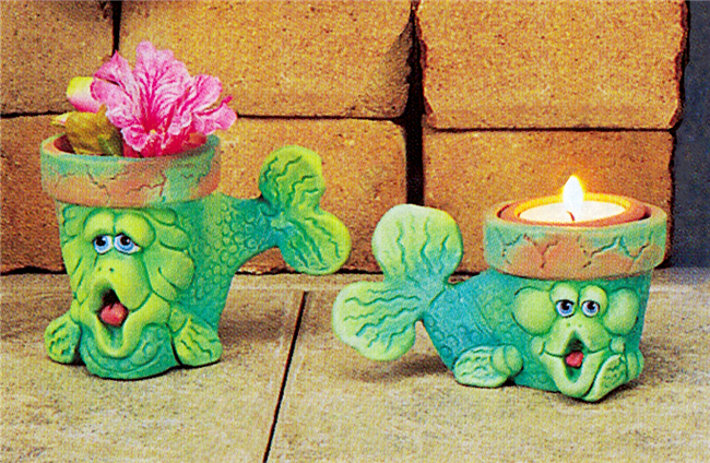 Two small cast ceramic pots shaped like cartoonish fish. Their heads and bodies are the pots, with the rims visible above their eyes.  They both look forward with fins and tails to the side and wide open mouths. The left pot is slightly taller.