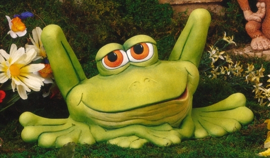 A cast ceramic statue of a cartoonish frog. It sits, bent back legs protruding well above its head. It looks forward with lidded eyes and a lazy grin. Its arms are folded under its chin.