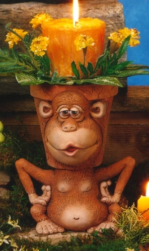 A cast ceramic pot made to resemble a cartoonish monkey. Its head forms the pot, with the rim just visible behind its forehead and round ears. It looks forward, lips pursed and open. It is seated with arms bent and held upward, hands at its sides.