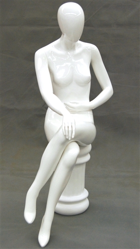 Female egghead mannequin in seated pose. Her legs are crossed with her hands on her lap.