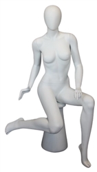 Female egghead mannequin in seated pose. Her legs are crossed with her hands on her lap.