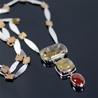 Burning Embers Necklace photo. Silver structure, the string has silver thins in long almond shapes with squares of bronze in between and the pendant has three stones: rectangular and squared rutilated quartz and an oval cornelian. Fiery complection!