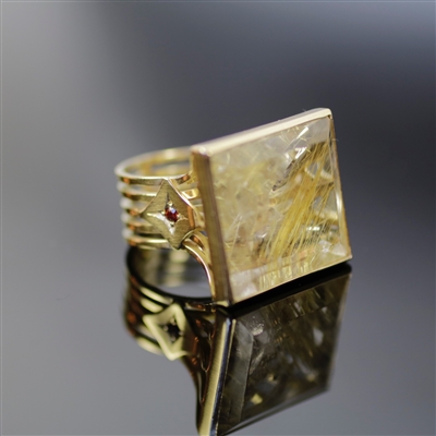 Majestic Tabletop Ring photo. beautifully structured 18k yellow gold shines with royalty with the strong, squared shaped rutilated quartz and the red garnet on the side details the sophisticated tabletop perfectly.