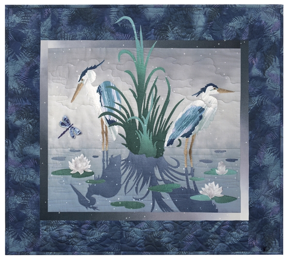 Quilt block of two blue herons standing in a pond, surrounded by lily pads and a dragonfly.