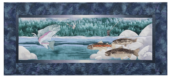 Quilt block of a fisherman catching a rainbow trout that is jumping out of the water, while other trout swim near the river rocks