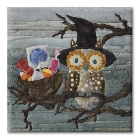 Quilt block of a wide-eyed owl and its nest full of candy