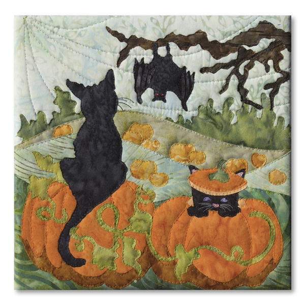 Quilt block of two black cats in a pumpkin patch, with a bat hanging from a tree and the large moon behind.