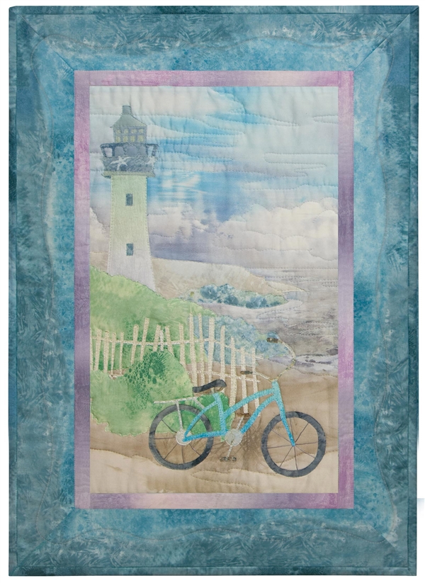 Quilt block of a bicycle leaning on a white picket fence, with a path leading up to the lighthouse that overlooks the ocean.