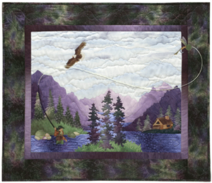 Quilt block showing a fisherman standing in a river casting a fly, with an eagle flying overhead. The riverside cabin and large purple mountains are in the background.