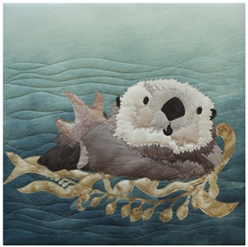 Quilt block of an otter swimming with a snack on her tummy.