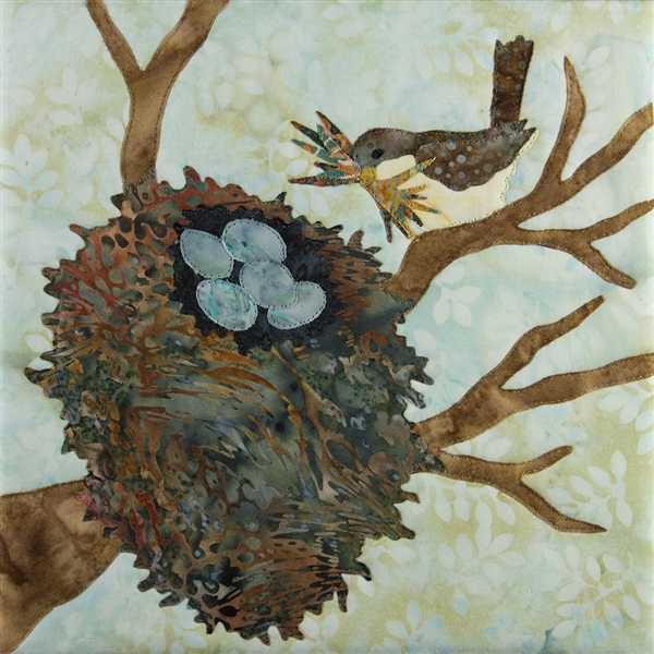 Quilt block with a bird returning to its nest snuggled in tree branches where 5 blue eggs lay