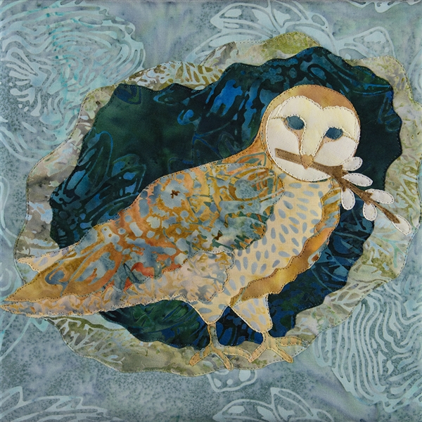 Quilt block with an owl holding pussy willow stems on a blue background