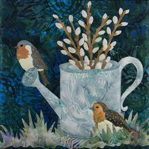 a quilt block with two speckled birds sitting on a tin watering can that is nestled in the grass and full of pussy willow branches.