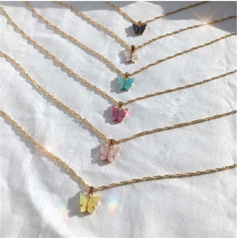 Six different Mirajo Jewelry butterfly necklaces on a white cloth