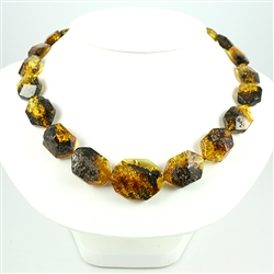This beaded amber necklace features shades of honey, green, and cherry Amber. The beads are hexagonal and slightly faceted.