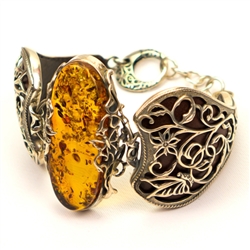 Antiqued silver surrounds this stunning amber nugget (1" x 2" x .25" - 2.5cm x 5cm x 1.8cm). Silver and brown leather hard band fits a wrist up to 7" - 18cm diameter (adjustable).
