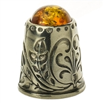 A beautifully designed silver thimble topped with amber.  Size approx 1" x .75".