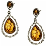 Artistic antique oval shaped silver earrings with a center of honey colored amber. Approx 1" long.