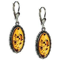 Artistic antique oval shaped silver earrings with a center of honey colored amber. Approx 1" long.