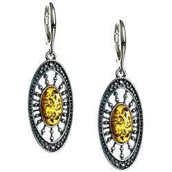 Artistic antique oval shaped silver earrings with a center of honey colored amber.