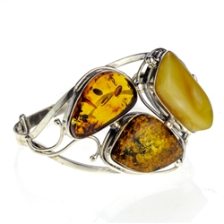 This sterling silver bracelet features a gorgeous cluster of mixed amber colors. Bracelet Size is 7" diameter.  Cabochon cluster measures approx 1.5" x 2".