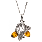 Sterling silver oak leaves hold two honey amber acorns. Pendant size is approx. 1" h x .75" w.