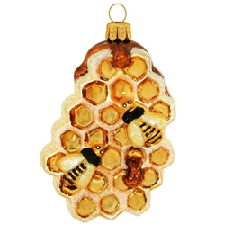 Bees buzz busily around the hive in this sweet glass design. Hand-painted with gold and amber glazes and iridescent glitter accents, this 3" honeycomb ornament is a bee-autiful choice for your nature themed tree! Handcrafted in Poland.