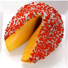 Giant fortune cookie dipped in dark chocolate and decorated with red hearts and white sprinkles.