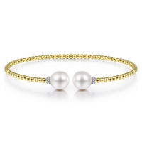 This 14k yellow gold bangle features pearls and diamonds.