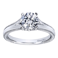 This split shank solitaire engagement ring with a touch of metalwork on the sides shows off a round center diamond of your choice! Available in white gold or platinum.