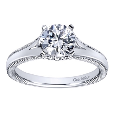 This split shank solitaire engagement ring with a touch of metalwork on the sides shows off a round center diamond of your choice! Available in white gold or platinum.