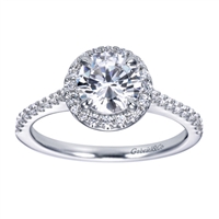 Round brilliant diamonds grace this contemporary halo engagement ring with shine, and the round halo at its center cushions and lifts a round center diamond of your choice.