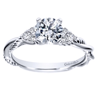 This sleek criss cross diamond engagement ring wraps around itself as white gold or platinum bands make their way up to a round center diamond in this contemporary diamond engagement ring.