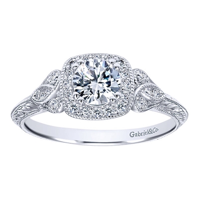 This vintage style diamond engagement ring showcases a decorated halo with an included round center diamond flashing brilliantly in the middle of this artistic diamond engagement ring.