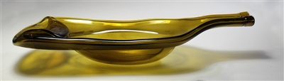 A glass tray made from an olive-green wine bottle that has been slumped into a tray shape. The tray is shown in profile against a gray background as light shines through it from above.