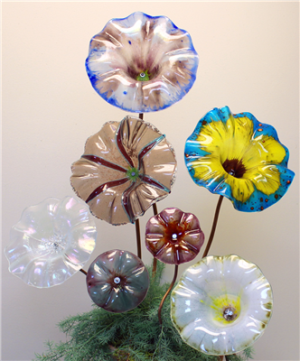 A large transparent glass flower on a grey background. The flower is a pale red-purple with a bright green center. There are opaque oval decorations mimicking the shape of petals. These have bright red centers with soft teal outlines.