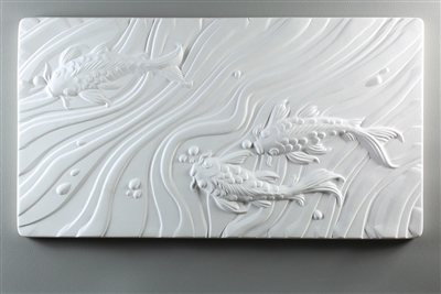 A long rectangular tile made of white ceramic. The carved texture on it shows a top-down view of three koi fish, two at the bottom right and one in the top left. The remainder of the space is filled with waving watery lines and a few round bubbles.