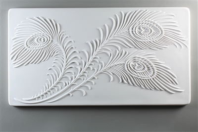 A long rectangular tile made of white ceramic. The carved texture is filled with three large peacock feathers. The base of the feathers starts in the bottom left corner and the feathers spread from there to occupy the whole texture.