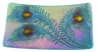 A rectangular dish made of iridescent glass. It has three large peacock feathers embossed on it that have been highlighted with shades of blue and purple. The eyes of each feather are yellow, and the base glass has a purple and green iridescent sheen.