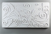 A long rectangular tile made of white ceramic. The carved texture has five dragonflies of various sizes in various places on the tile surrounded with curling lines. The curling lines suggest movement across the tile from left to right.