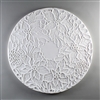 A circular tile made of white ceramic. The carved texture has a ring of five poinsettia flowers with additional leaves and pinecones surrounding the edges, leaving a small circle in the very center of the tile empty and blank.
