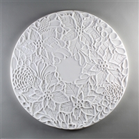 A circular tile made of white ceramic. The carved texture has a ring of five poinsettia flowers with additional leaves and pinecones surrounding the edges, leaving a small circle in the very center of the tile empty and blank.