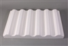 A long rectangular white ceramic mold for fusing glass on a grey background. There are six raised ridges equally spaced along the length of the mold. Each ridge is angled like half a hexagon, and the valleys between them are shaped in the inverse.