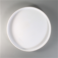 A circular white ceramic mold for fusing glass on a grey background. The mold has a narrow wall around its edges and the remainder is completely flat.