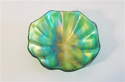 An octagonal bowl made from iridescent green glass. The bottom of the bowl is fluted into many symmetrical ridges radiating outwards from the center.
