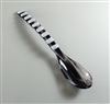 A fused glass spoon on a grey background. The spoon is mostly black glass with a few white streaks, and the handle is decorated with small rectangles of white spaced evenly apart.