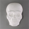 A white ceramic mold for fusing glass on a grey background. The mold has been shaped and carved into the front view of a human skull. It is overall raised and dome-shaped, with the eyes, nose, and other details carved inwards.